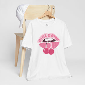 White t-shirt with pink 'Girl Gang' graphic on a wooden chair against a white background