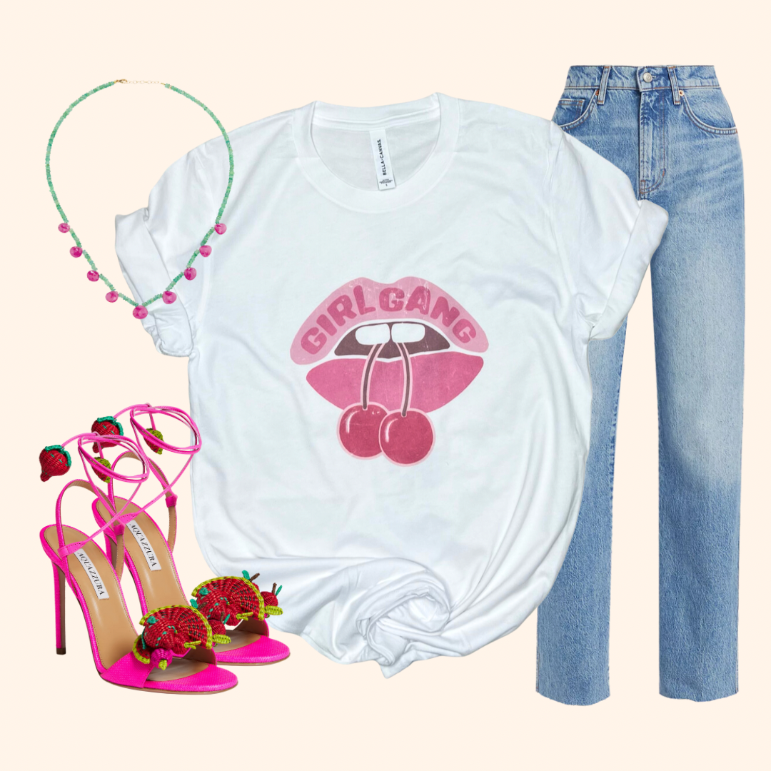White t-shirt with 'Girl Gang' graphic, pink high heels, blue jeans, and a green headband on a white background.