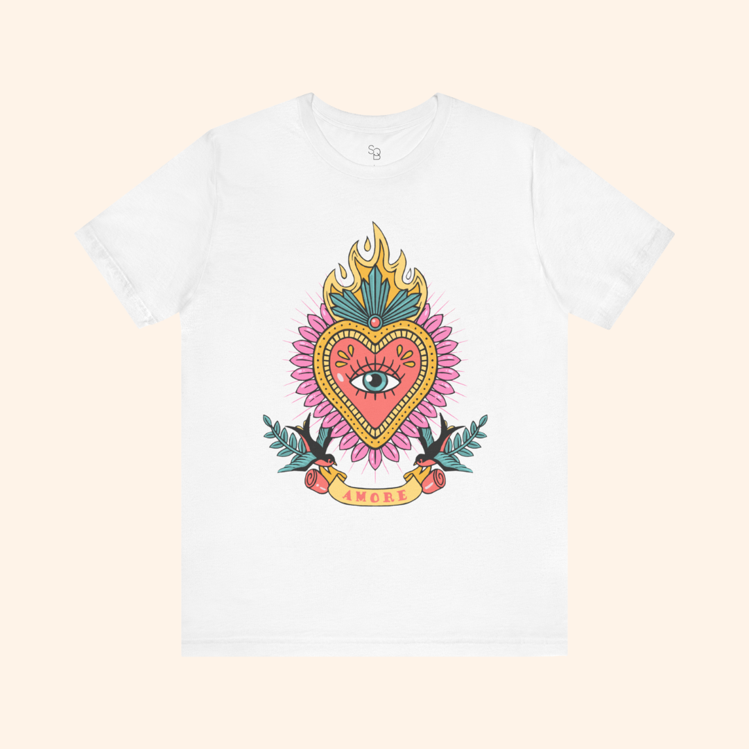 White sacred heart graphic tee in flat lay, centered design with eye inside heart, swallows and roses at base; casual street style fashion shirt.