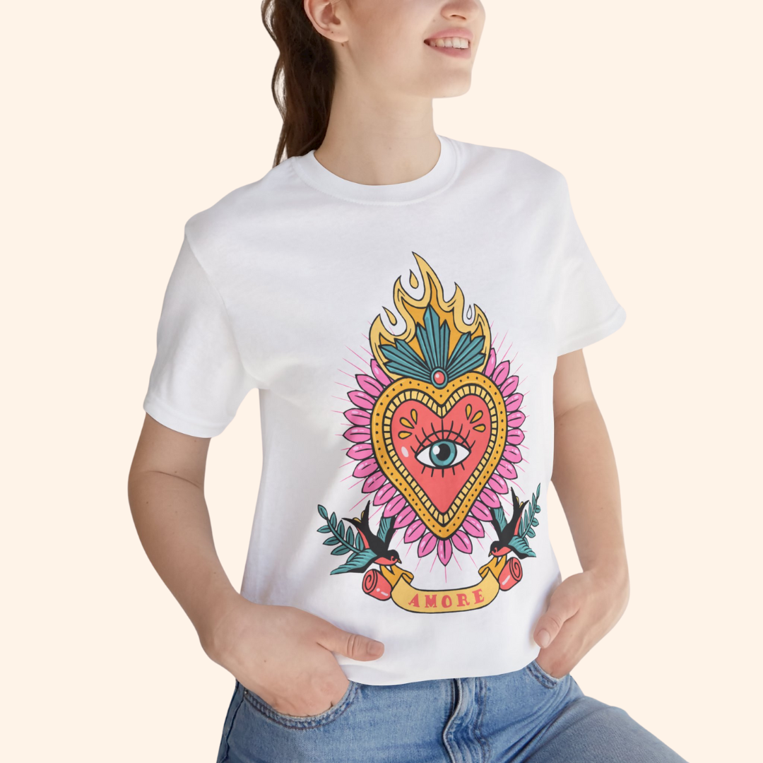 Close-up of model in white Amore T-Shirt highlighting flaming heart and eye motif; soft cotton streetwear top styled with denim.