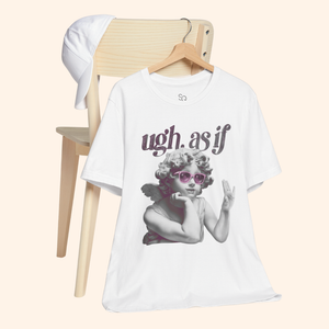 White street style graphic tee with angel design hanging on wooden chair beside white cap, minimalist aesthetic perfect for modern wardrobe display.