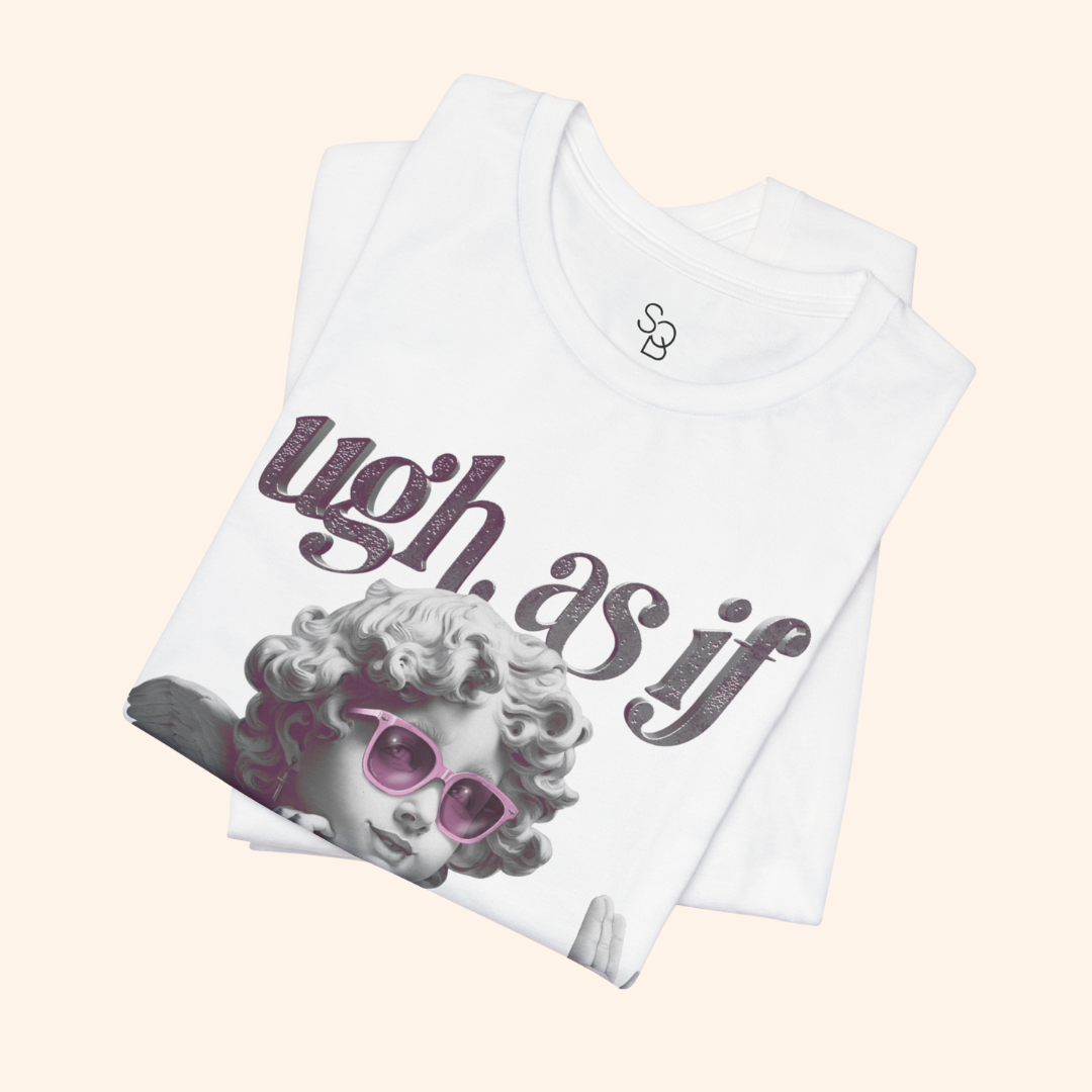 Folded white statement tee showing angel graphic and pink sunglasses detail, emphasizing premium cotton fabric and neat packaging style.