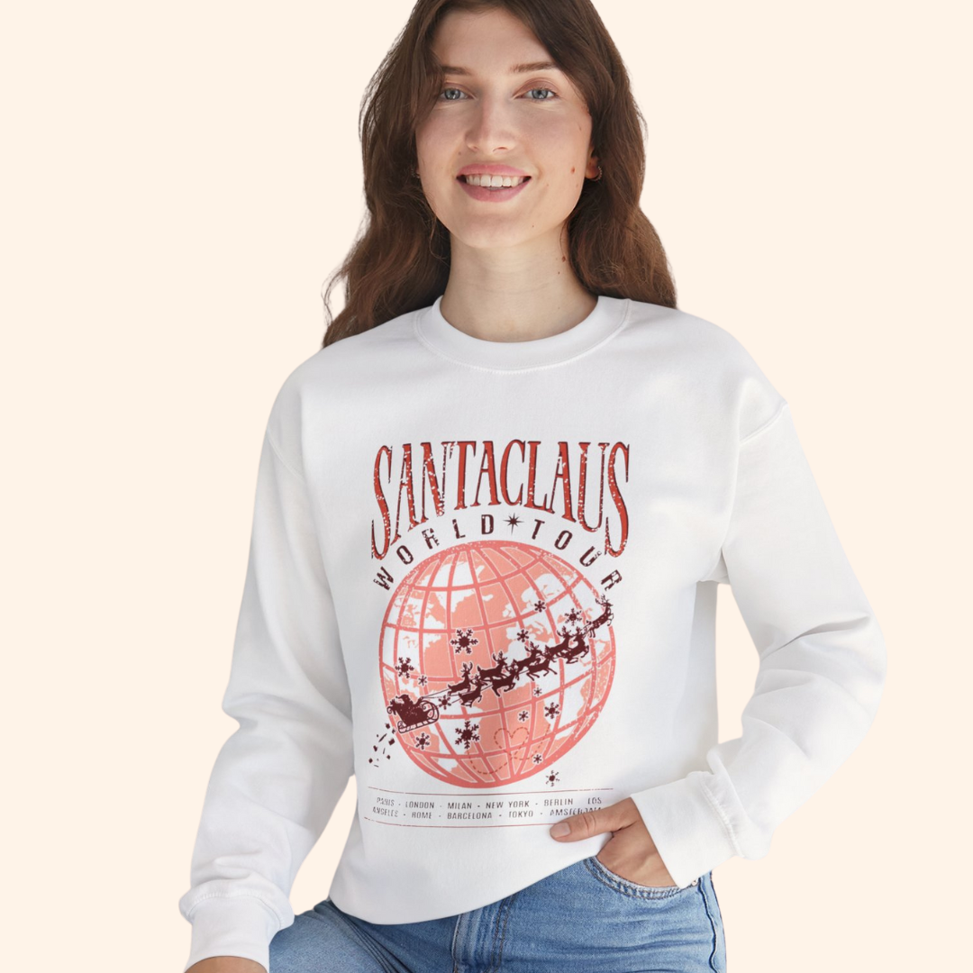 Model wearing Santas World Tour sweatshirt with jeans, smiling and relaxed pose, showing full front red globe tour print, cozy holiday graphic sweatshirt for women, casual streetwear look.