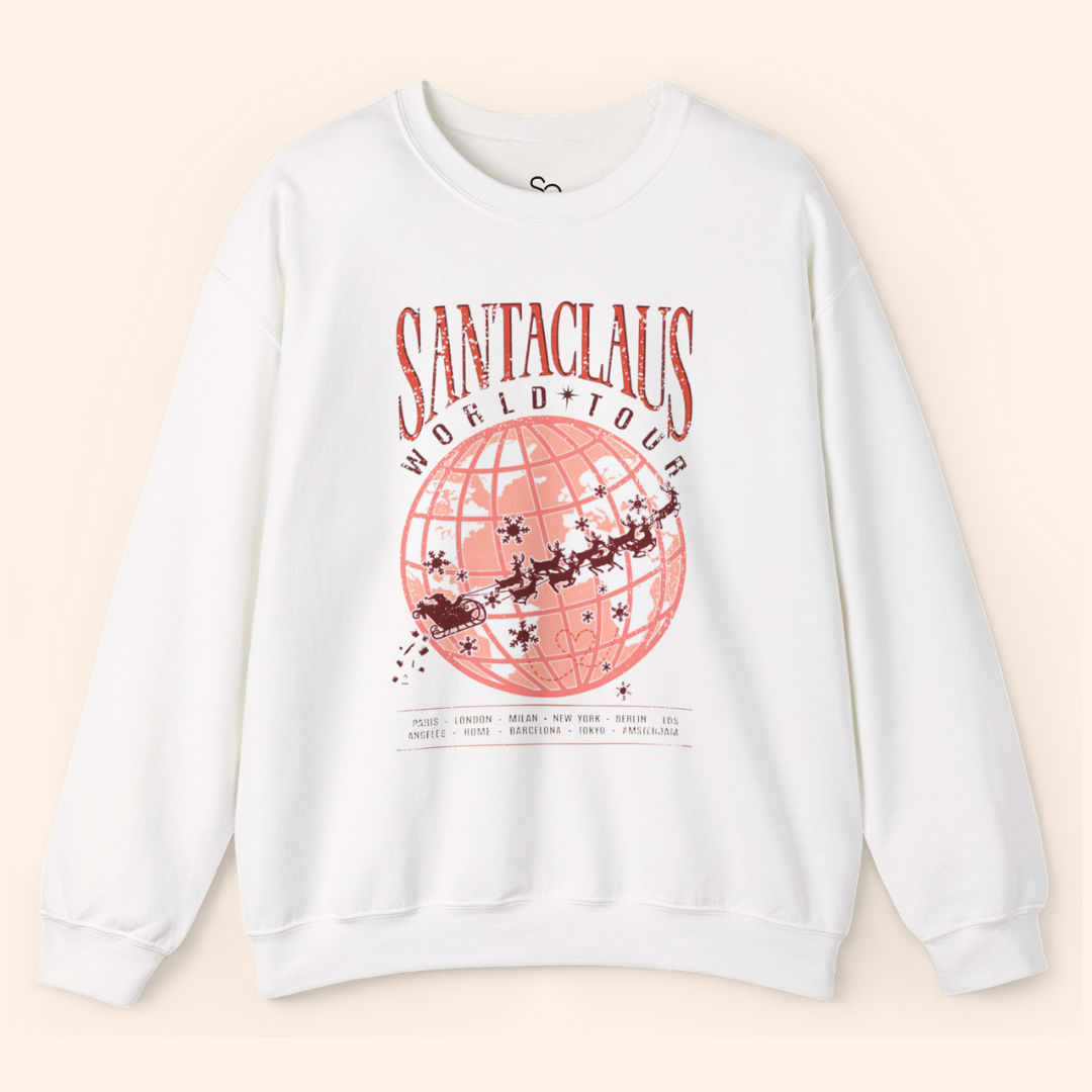 White Santas World Tour sweatshirt laid flat on soft beige background, featuring red globe graphic with Santa’s sleigh across major cities, unisex fit, cotton-poly blend, Christmas streetwear vibe.
