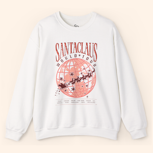 White Santas World Tour sweatshirt laid flat on soft beige background, featuring red globe graphic with Santa’s sleigh across major cities, unisex fit, cotton-poly blend, Christmas streetwear vibe.