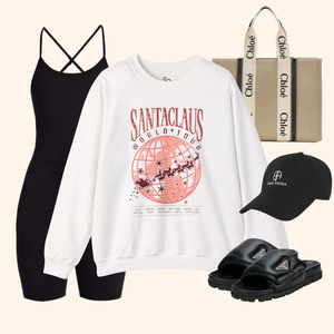 Styled outfit with Santas World Tour sweatshirt paired with black romper, beige designer-style tote bag, black slide sandals, and black baseball cap, modern streetwear holiday outfit layout.
