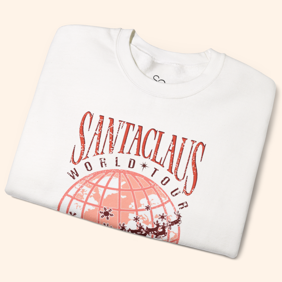Folded white Santas World Tour sweatshirt showing vintage-style tour graphic with red world map and Santa’s sleigh, cozy cotton-poly fabric, holiday graphic sweatshirt detail.