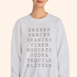 Tight chest-up view of a heather gray crewneck showing stacked black lettering that reads DASHE R DANCER PRANCER VIXEN MOSCATO VODKA TEQUILA BLITZEN; clean neutral background highlighting print detail and fabric texture.