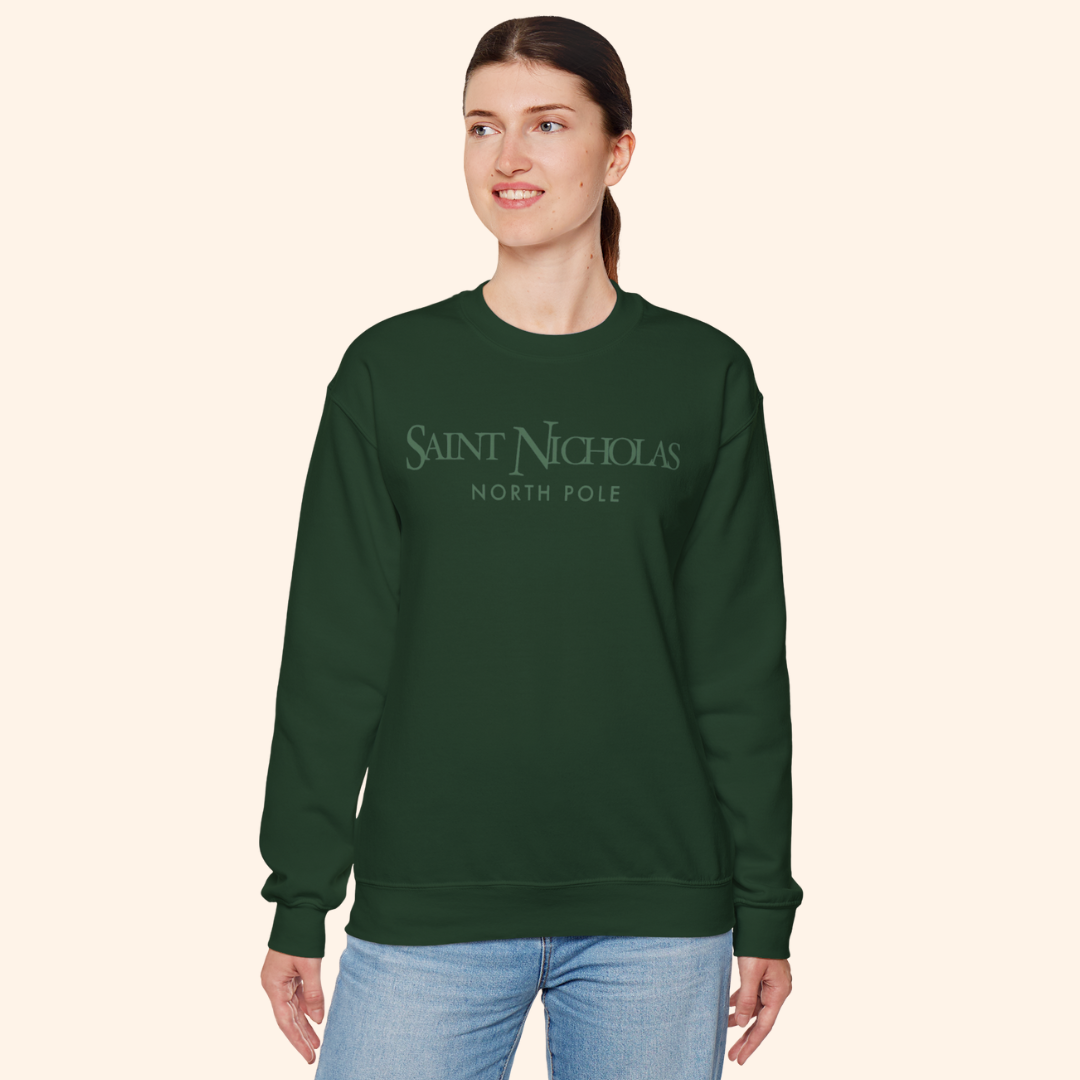Model standing in Saint Nicholas Christmas Sweatshirt, forest-green color, relaxed unisex fit; styled for cozy holiday fashion and everyday wear.