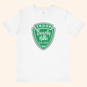 White Troops graphic tee styled in a minimal flat lay showing the front green badge print, casual streetwear look, soft cotton fabric.