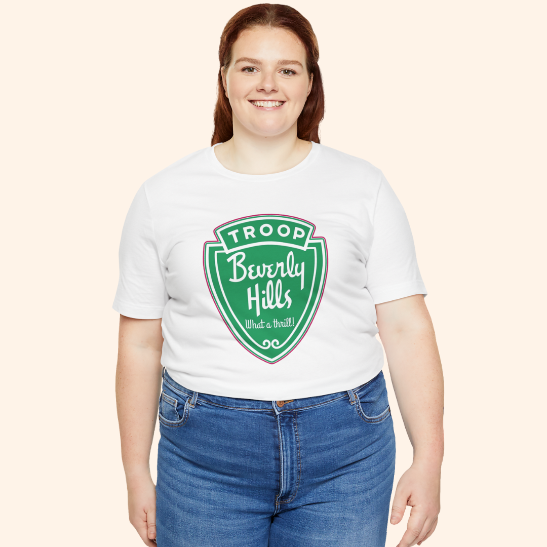 Plus size model wearing the Troops graphic tee in white cotton with green retro badge print, styled with jeans for a casual look.