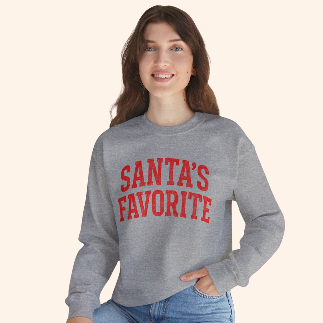 Woman wearing the Santas Favorite sweatshirt styled with denim for an easy holiday look. The relaxed crewneck fit and bright red graphic make the festive pullover the focal point of the outfit, showcasing casual winter style.