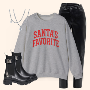 Santas Favorite sweatshirt styled with black leather pants, chunky black boots, and layered silver necklaces. Full winter outfit inspiration showing how the holiday pullover pairs with chic seasonal wardrobe staples.