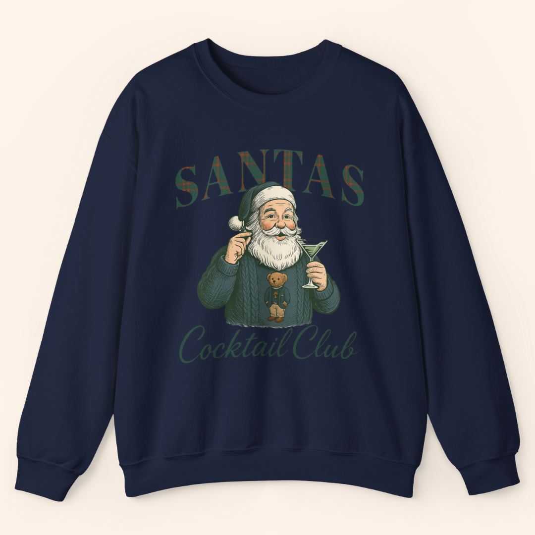 Navy holiday graphic sweatshirt featuring a vintage style Santa holding a martini with plaid lettering that reads Santas Cocktail Club, displayed as a flat lay on light background.