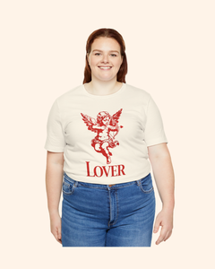 Plus size model wearing a natural color graphic tee featuring red cupid cherub artwork and lover text, front facing view.