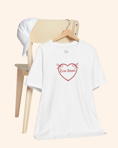 White graphic t shirt hanging from a wooden chair in a casual lifestyle setting, styled for everyday streetwear.