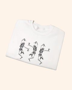 Folded white Three Is Company sweatshirt with dancing skeleton graphic