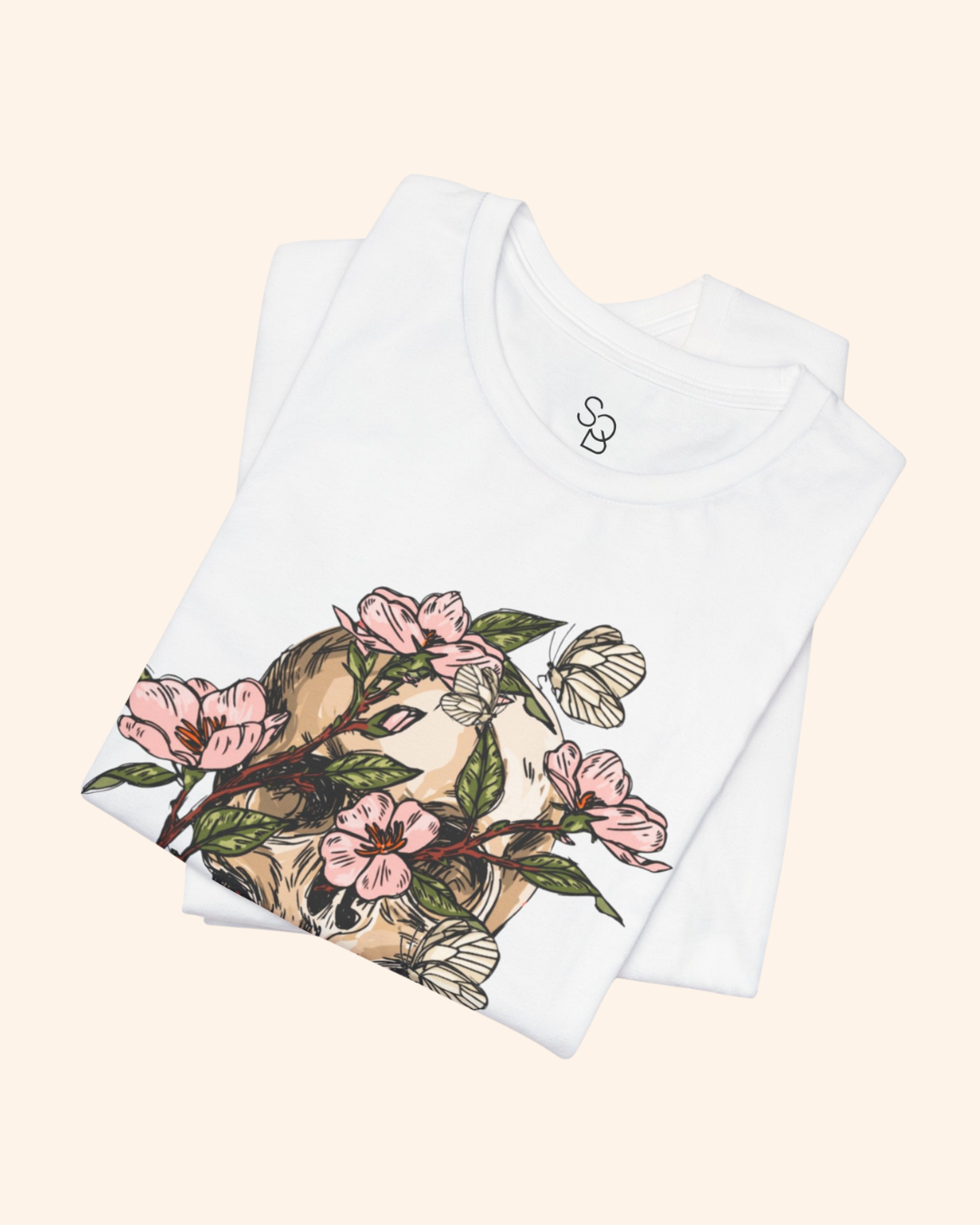 Folded white Spring With You tee showing pink blossoms and botanical skull design