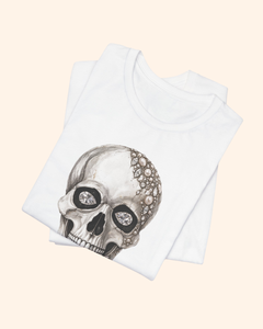 Folded white Shine Bright tee showing illustrated diamond eyes and pearl details