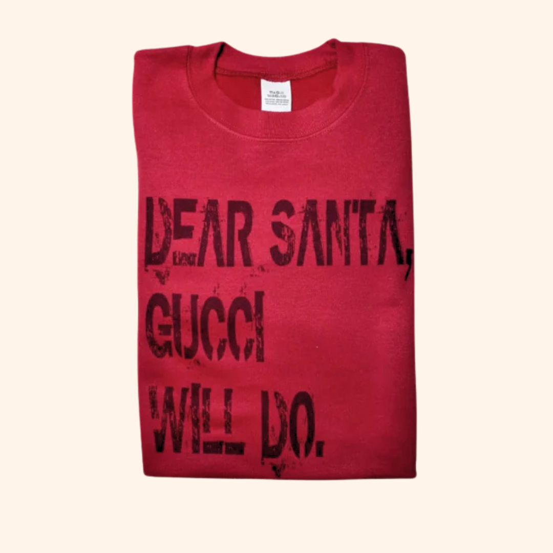 Folded red “Dear Santa” sweatshirt on a neutral surface, displayed as a solo flat lay product image.

