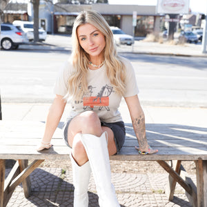 Galloping With You tee styled with white boots and mini skirt, posed outdoors for country concert style.

