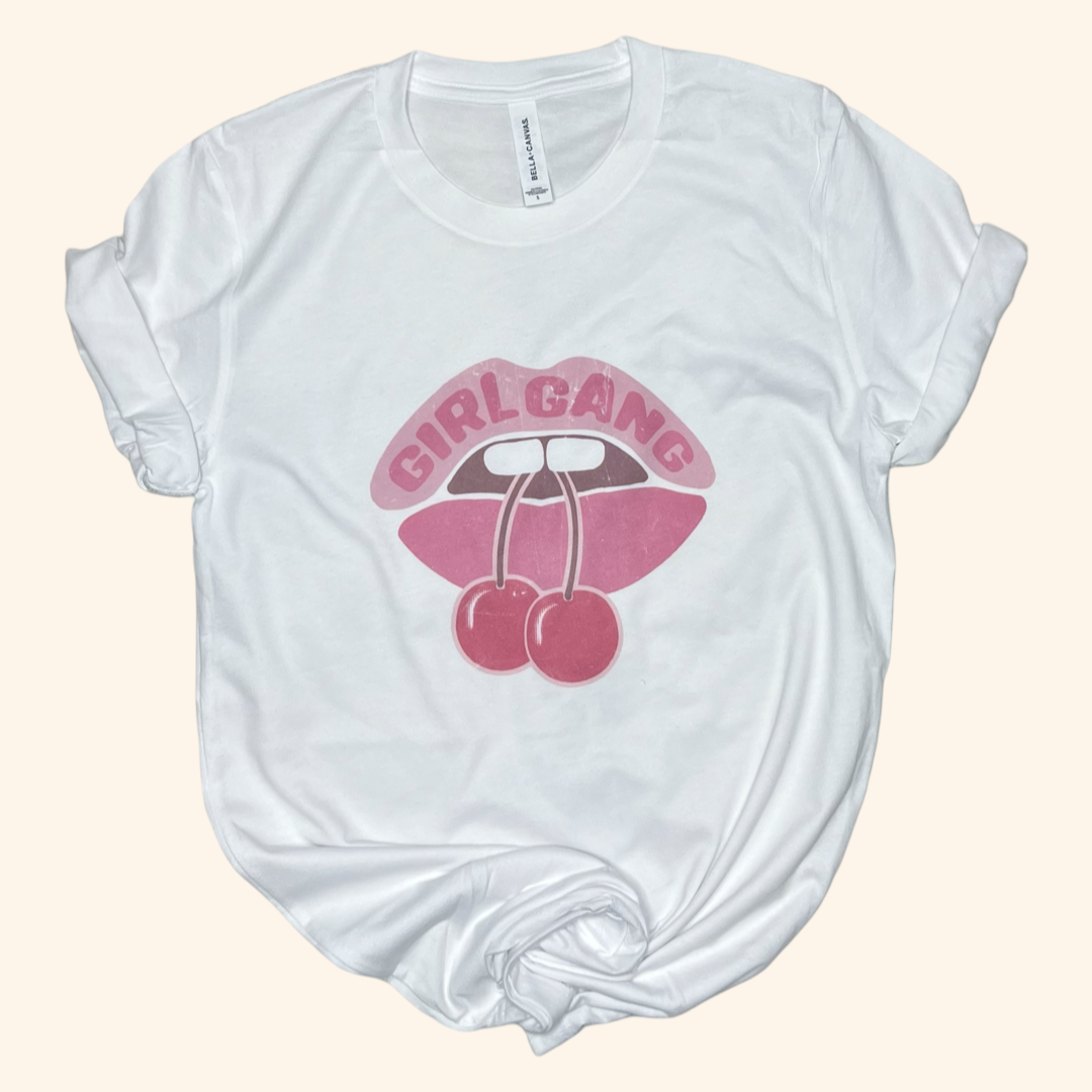 Flat lay of white Girl Gang cherry lips tee, cotton graphic shirt for women and best friend gifting.