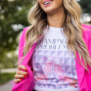 Model wearing Champagne Problems shirt with feathered pink blazer and heels for a bold girls night or party outfit.


