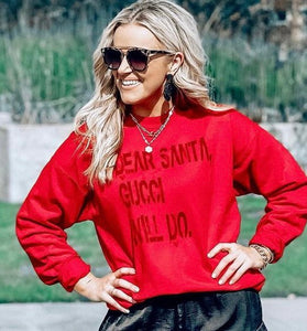 Close-up of woman outdoors wearing red holiday sweatshirt, black sunglasses, and layered silver necklaces with holiday accessories.

