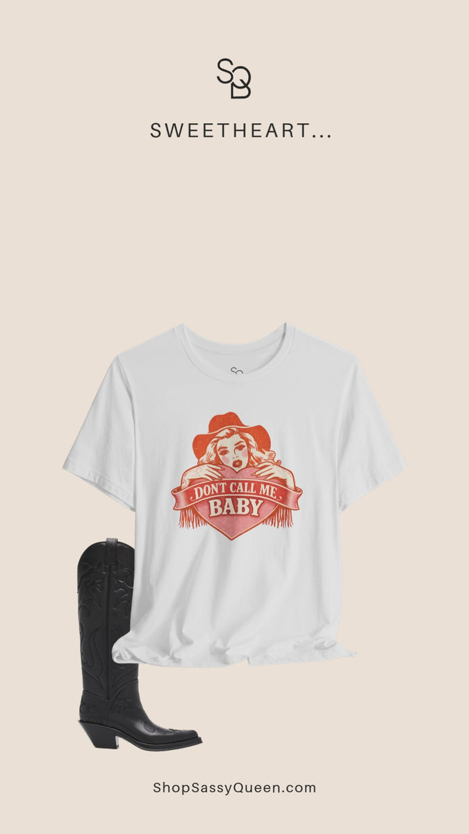 Styled flat lay of white Don’t Call Me Baby western graphic t-shirt with boots, hat, and accessories.