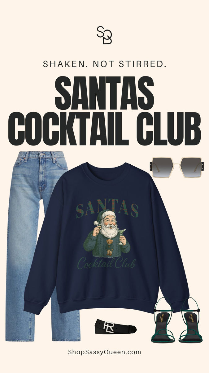 Holiday outfit flat lay featuring navy Santas Cocktail Club sweatshirt paired with denim, green heels, sunglasses, and black belt for chic winter styling.