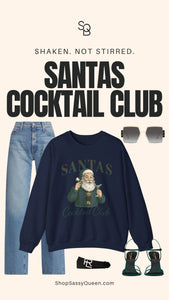 Holiday outfit flat lay featuring navy Santas Cocktail Club sweatshirt paired with denim, green heels, sunglasses, and black belt for chic winter styling.